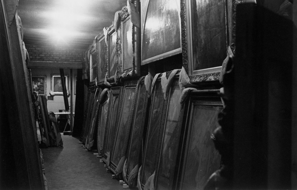 National Gallery paintings in storage in the Manod caves, hanging in two rows on racks, with padding wrapped around their corners. Photo: © The National Gallery London.