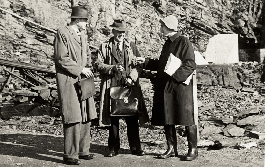 Three men - from left to right, Ian Rawlins of the National Gallery, Mr Vaughan the quarry manager, and Martin Davies of the National Gallery, standing talking outside the entrance to Manod Quarry, Wales.